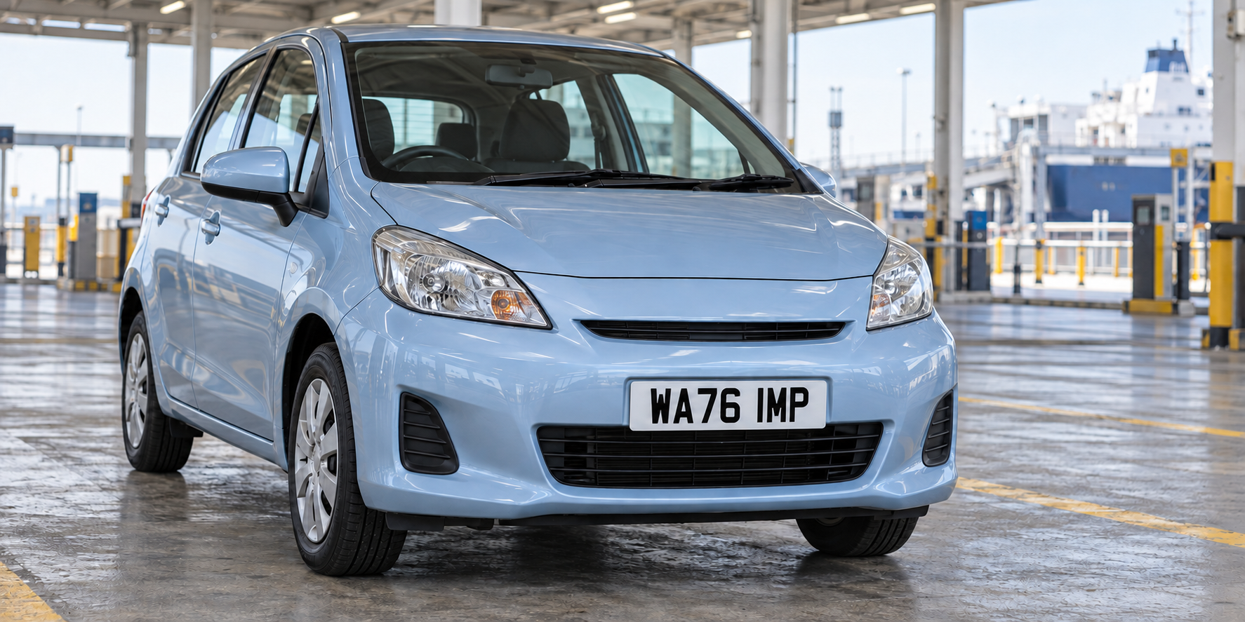 Pale blue imported city car in a ferry-terminal inspection bay with a complete white WA76 IMP plate fitted in its compact front recess